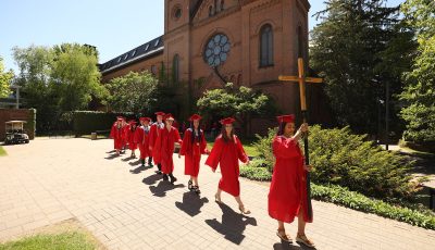 SJP graduates walking in line behind cross