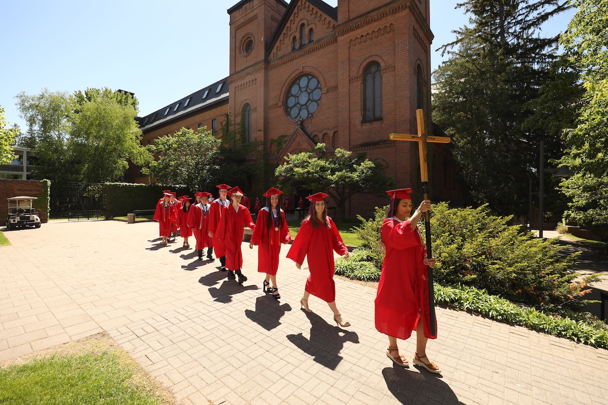 SJP graduates walking in line behind cross