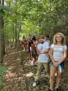 saint john's prep students lined up on wooded trail smiling at camera