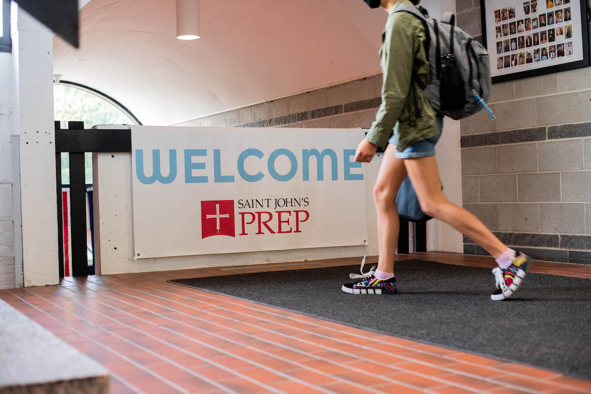 students walking in front of a sign saying 'welcome to saint john's prep'